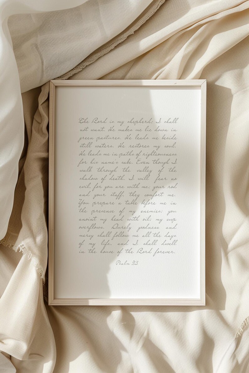 May include: A rectangular framed print featuring the text of Psalm 23 written in a cursive script. The frame is light-colored wood, and the paper is white with dark grey lettering. The text begins with The Lord is my shepherd and ends with Psalm 23.