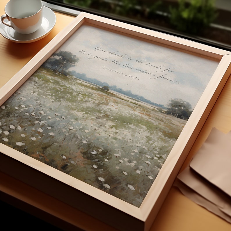 May include: A framed landscape print featuring a field of white flowers and trees under a cloudy sky. The artwork is in a light wood frame. Text at the top reads "Give thanks to the Lord, for He is good; His love endures forever. 1 Chronicles 16:34."