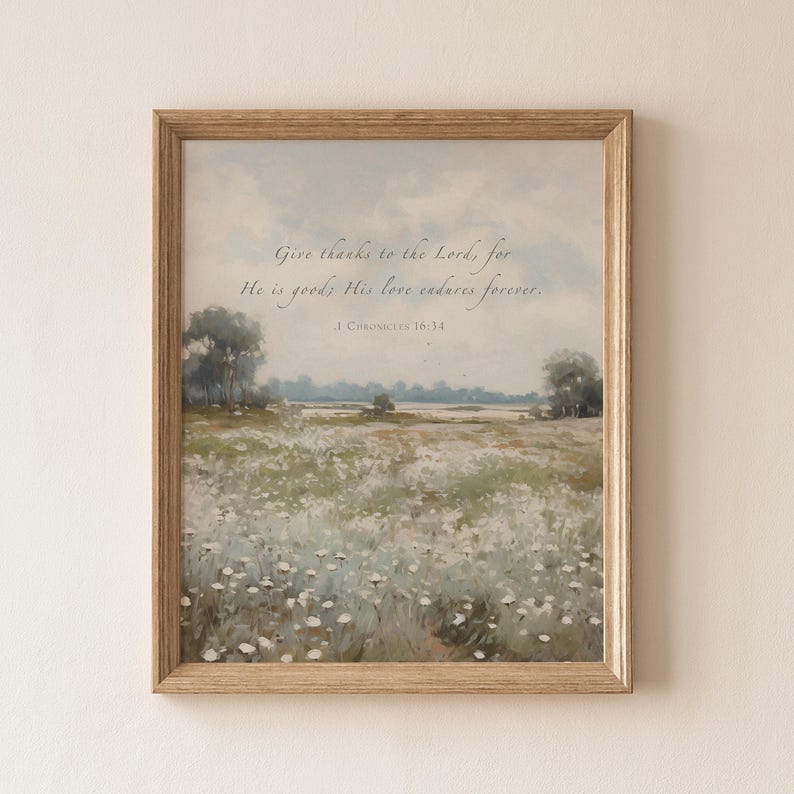 May include: A framed print featuring a pastoral landscape with a field of white flowers under a soft blue sky. The artwork includes the text "Give thanks to the Lord, for He is good; His love endures forever. 1 Chronicles 16:34."