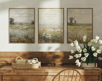 Op de afbeelding: Drie rechthoekige wandkunstprints met landschapsschilderijen van velden met wilde bloemen in gedempte groen-, bruin- en wittinten. Elke print bevat gedrukte tekst met religieuze verzen. De prints zijn ingelijst in dunne houten lijsten.
