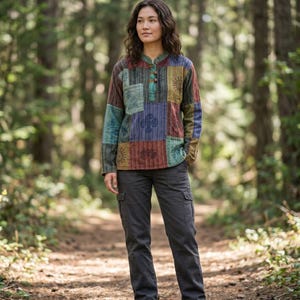May include: A woman wearing a patchwork long-sleeve shirt with a button-up collar and dark gray cargo pants. The shirt features a variety of colorful, patterned squares. The pants have multiple pockets and a straight leg. The person is wearing brown boots.