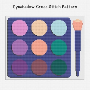 May include: A cross-stitch pattern of an eyeshadow palette with nine colorful circles in shades of pink, orange, teal, purple, and brown. A matching makeup brush is positioned to the right. The text "Eyeshadow Cross-Stitch Pattern" is at the top.