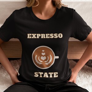 May include: Black t-shirt with the text "EXPRESSO STATE" in a light brown colour. A stylised coffee cup with hearts and a laurel wreath is in between the words.