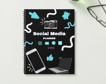 May include: A black spiral bound notebook with a social media planner design. The cover features a camera, a smartphone, a laptop, and various social media icons. The text "Social Media Planner" is printed in white on the cover.