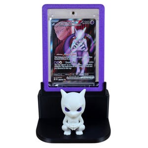 May include: A purple and black display stand holding a Pok&eacute;mon trading card featuring Mewtwo EX. A white Mewtwo figurine sits on the base of the stand. The card is encased in a purple frame.