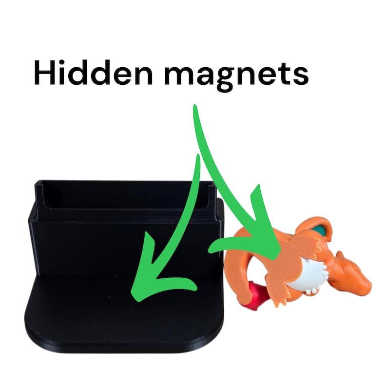 Puede incluir: Un soporte negro rectangular con una base curva y una figura naranja y blanca. El texto "Hidden magnets" est&aacute; encima del soporte. La figura es naranja con detalles blancos y rojos.