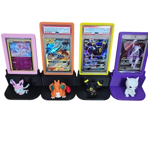 Puede incluir: Cuatro expositores de cartas Pok&eacute;mon en rosa, naranja, amarillo y morado. Cada soporte contiene una carta Pok&eacute;mon clasificada y una figura correspondiente. Las cartas son de la serie Pok&eacute;mon Sol y Luna.