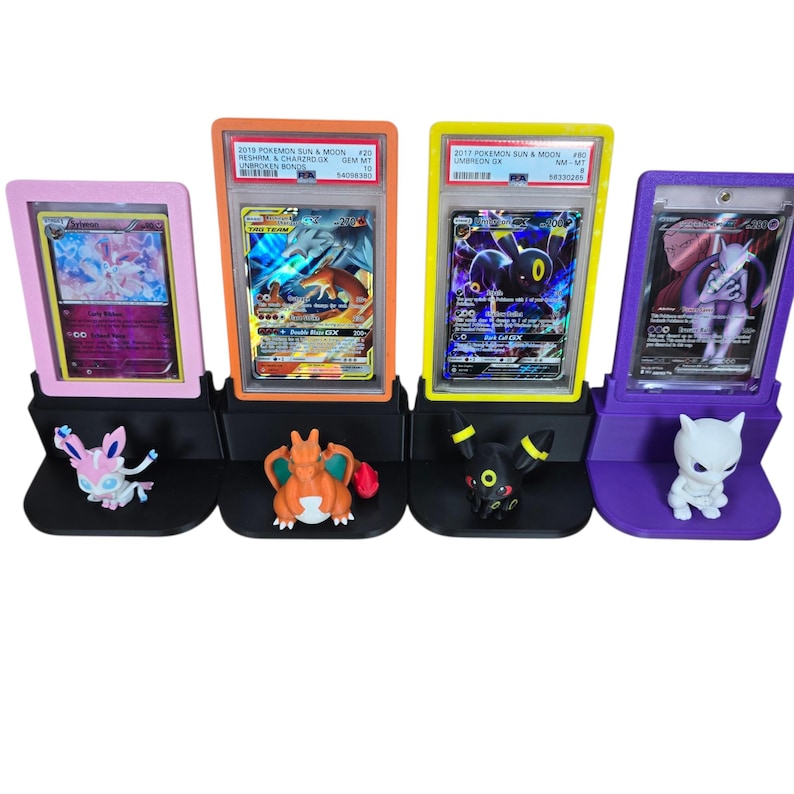 Puede incluir: Cuatro expositores de cartas Pok&eacute;mon en rosa, naranja, amarillo y morado. Cada soporte contiene una carta Pok&eacute;mon clasificada y una figura correspondiente. Las cartas son de la serie Pok&eacute;mon Sol y Luna.