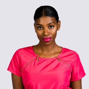 Puede incluir: Una blusa rosa brillante de manga corta con cremalleras doradas en el escote. La blusa se combina con una falda blanca. La modelo tiene el pelo oscuro y lleva pintalabios rosa.