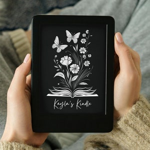 May include: A black e-reader with a white floral design and butterflies. The text "Kayla's Kindle" is displayed on the screen.
