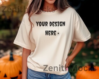 May include: A white t-shirt with the text "YOUR DESIGN HERE" and a small black spider hanging from the text. The shirt is being worn by a person with long brown hair.