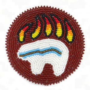 May include: Round beaded design featuring a white bear with blue and gold accents, and a bear claw design in black, red, yellow, and orange. The border is made of small red beads.