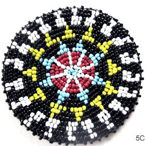 Peut inclure: Un motif rond en perles avec un fond noir et un centre coloré. Le centre présente un motif rouge, blanc et bleu avec des accents jaunes. La bague extérieure est noire avec des perles blanches et jaunes.