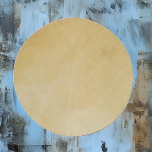 May include: A round, light beige, textured circle against a blue and gray background.
