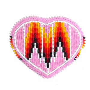 May include: A pink heart-shaped beaded ornament with a colourful flame design in the centre. The flame design is made with red, orange, yellow, and black beads.