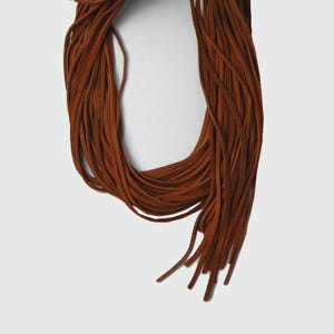 May include: A bundle of brown leather cords, tied together at the top and fanned out at the bottom.