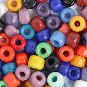 May include: A collection of colorful plastic beads in various shades of blue, red, green, yellow, purple, and orange. The beads are round and have a hole in the center for stringing.