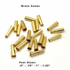 May include: A collection of brass cones in four sizes: 0.5 inches, 0.75 inches, 1 inch, and 1.25 inches. The cones are scattered on a white surface.