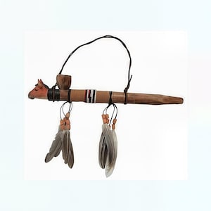 May include: A wooden tobacco pipe with a horse head carving at one end. The pipe features a brown finish, decorative bands, and hanging feathers. A black cord is attached for carrying. The pipe is a traditional Native American craft.