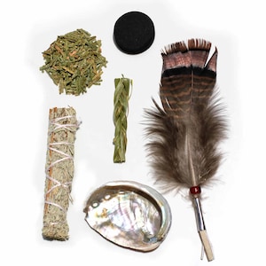 May include: A collection of spiritual items including a sage bundle, a feather, a shell, a charcoal disc, and dried herbs. The feather is brown and tan with a red bead. The shell has iridescent colours.