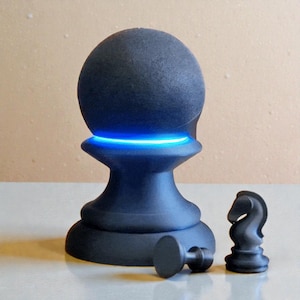 May include: A black chess piece with a glowing blue light, resembling a pawn, sits next to a knight and a small piece. The spherical top of the pawn is textured. The knight and small piece are also black.