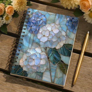 May include: Spiral-bound notebook featuring a stained-glass design of blue and white hydrangeas. The notebook has a black spiral binding and is accompanied by a gold pen. The floral design includes green leaves and is set against a light blue background.