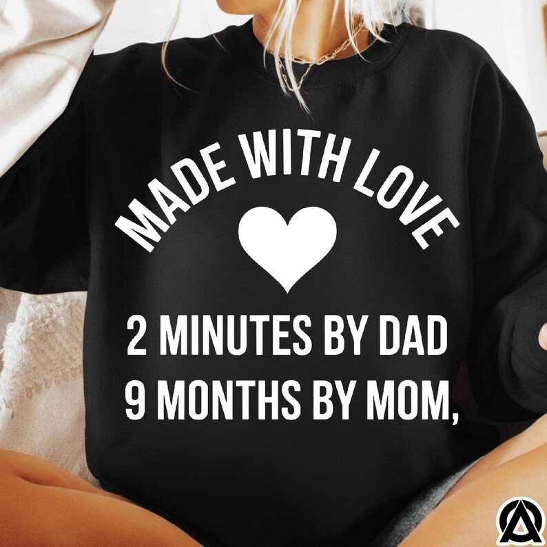 May include: Black sweatshirt with the text "MADE WITH LOVE" above a white heart. Below the heart, the text reads "2 MINUTES BY DAD 9 MONTHS BY MOM,"