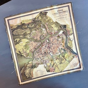 May include: A vintage map of St. Petersburg, Russia, printed on fabric. The map shows the city's layout with rivers and canals, and the title "Plan of St. Petersburg" is printed in the upper right corner.