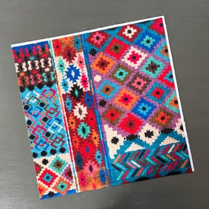 May include: A colorful fabric with a geometric pattern in shades of blue, red, orange, and purple. The fabric has a woven texture and a diamond-shaped pattern.