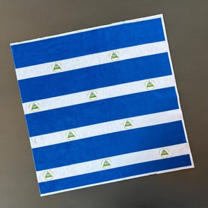 May include: A rectangular sheet with a blue and white striped pattern. The blue stripes alternate with white stripes, and each white stripe features a small emblem of a triangle within a circle.