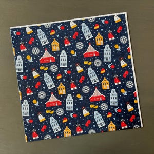 May include: Blue fabric with a repeating pattern of red, yellow, and blue houses, windmills, and clogs. The background is a dark blue with white dots.