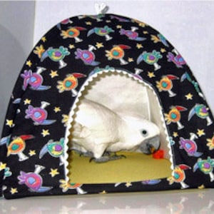 May include: A black bird-themed fabric bird tent with a white cockatiel inside. The tent has a white trim around the opening and a yellow floor.
