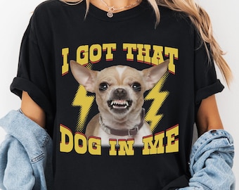 May include: Black t-shirt with a graphic of a snarling chihuahua wearing a collar. The text "I GOT THAT DOG IN ME" is in yellow, with yellow lightning bolt graphics on either side of the dog's head.