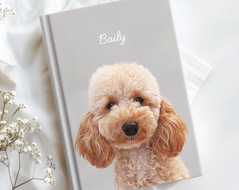 May include: A light grey notebook with the name "Baily" in script. The cover features a portrait of a curly-haired, light brown dog. The dog has dark eyes and a black nose. The notebook is on a white surface.