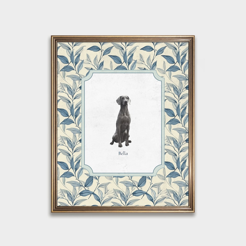 May include: A framed print with a blue and white floral pattern. The print features a photo of a grey dog sitting with the name "Bella" printed below the photo.