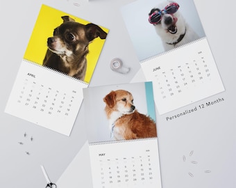 May include: A collection of three dog-themed wall calendars. Each calendar features a different dog portrait with a month displayed. The calendars are white with black text and spiral binding. The phrase "Personalized 12 Months" is printed on the image.