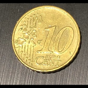 Könnte beinhalten: Eine goldfarbene 10-Cent-Euro-Münze mit der Aufschrift "EURO CENT" und einer Darstellung der Europäischen Union.