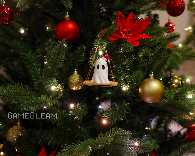 A side view of a white Santa ghost on a brown swing ornament hanging on a holiday Christmas tree with lights in the background.