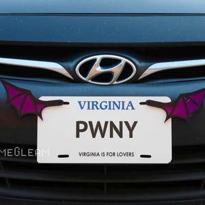 May include: A black car with a license plate that says "PWNY" and the state of Virginia. The license plate has two purple bat wings attached to it.