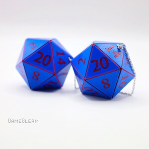 May include: Two blue twenty-sided dice with red numbers. The dice are connected by a silver chain.
