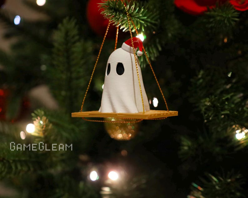 A side view of a white Santa ghost on a brown swing ornament hanging on a holiday Christmas tree with lights in the background.