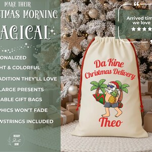 May include: A cream-colored Christmas gift bag with red drawstring closure. The bag features a cartoon of a pineapple wearing a Santa hat and sunglasses, holding a surfboard and pineapple. Text on the bag reads "Da Kine Christmas Delivery" and "Theo".