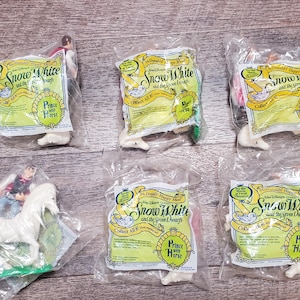 May include: Six plastic bags with a white background and colorful graphics. Each bag features a cartoon image of a prince on a horse and the text "Snow White and the Seven Dwarfs". The bags are part of a McDonald's Happy Meal promotion.