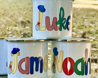 May include: White enamel mugs with silver rims, each personalized with a name in colorful, playful lettering. One mug is blank. The names include "Luke", "James", and "Noah", with decorative accents.