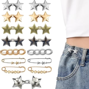 May include: A collection of star-shaped and chain-link decorative jean buttons and pins in silver, gold, and bronze tones. The pins and buttons are displayed on a white background, with a pair of silver star buttons attached to a denim waistband.