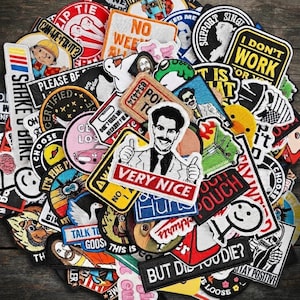 May include: A large collection of assorted embroidered patches featuring various pop culture references, cartoon characters, and text-based slogans. The patches are layered together in a dense pile, displaying a wide range of colors, shapes, and designs.