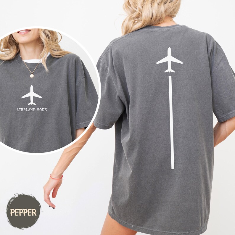 May include: Dark gray t-shirt with a white airplane graphic and the words "AIRPLANE MODE". The back of the shirt features a white airplane graphic with a white line extending downwards. The shirt is a comfortable, oversized fit.