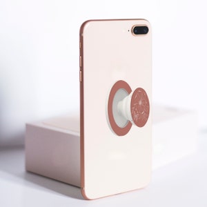 Rose Butterfly Collapsable Grip and Stand in White on peachy pink phone.