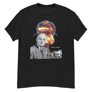 Può includere: T-shirt nero con un ritratto di Harry S. Truman e un'immagine di un fungo atomico. Il testo recita: "Surrender your beer or face the consequences of your actions." La maglietta è a girocollo.