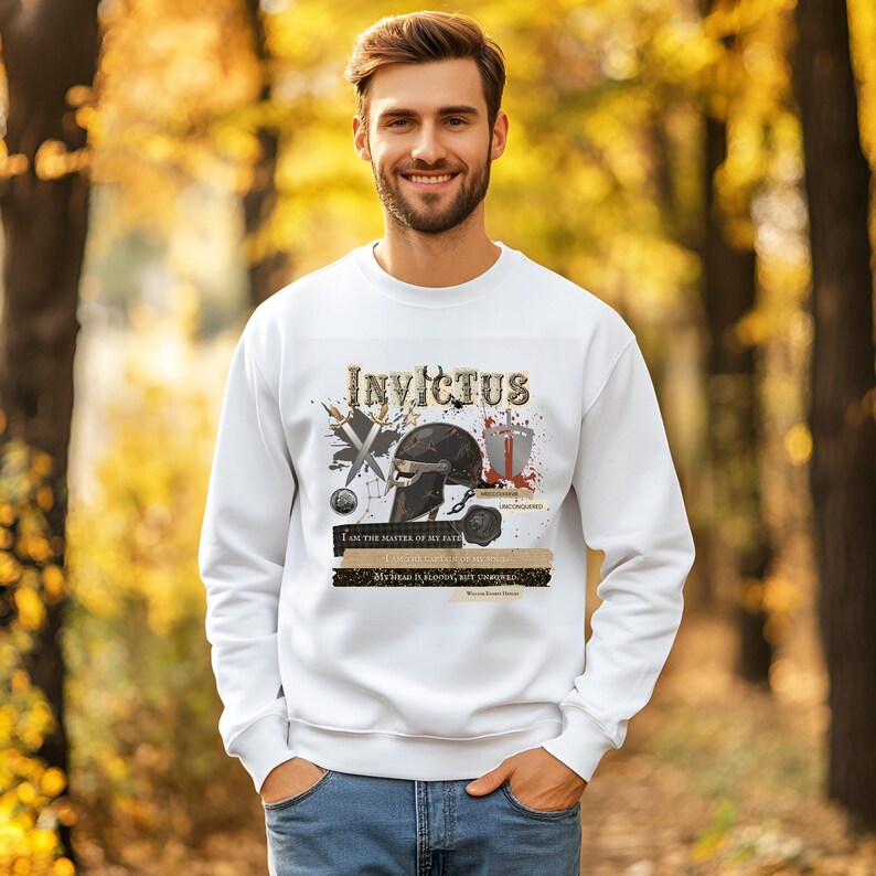 May include: White sweatshirt with the word "Invictus" in a stylized font. The graphic includes a black helmet, crossed swords, and text from the poem "Invictus". The sweatshirt is worn by a person in a natural outdoor setting.